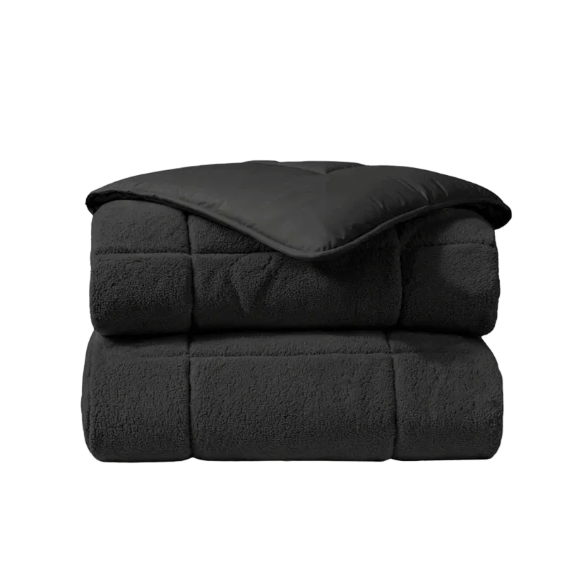 Het Zelesta Teddybed - Antraciet is een gevouwen dekbed met een gladde bovenkant en een zachte, fleece-achtige teddystof onderkant, afgebeeld tegen een witte achtergrond.