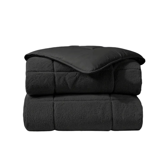 Het Zelesta Teddybed - Antraciet is een gevouwen dekbed met een gladde bovenkant en een zachte, fleece-achtige teddystof onderkant, afgebeeld tegen een witte achtergrond.