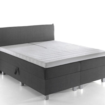 De Silver Line Split Topper - Hybrid Koudschuim is afgebeeld op een modern tweepersoonsbed met een donkergrijs gestoffeerd frame en hoofdbord, met een wit matras gemaakt van natuurlijke materialen voor stevige ondersteuning en een gezonde slaapomgeving.