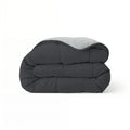 Het Zelesta Comfort Duo Dekbed heeft een netjes gevouwen ontwerp met een zachtzwarte buitenkant en zilvergrijze binnenkant, wat doet denken aan klassieke dekbedden, en wordt gepresenteerd tegen een effen witte achtergrond.