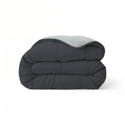 Het Zelesta Comfort Duo Dekbed heeft een netjes gevouwen ontwerp met een zachtzwarte buitenkant en zilvergrijze binnenkant, wat doet denken aan klassieke dekbedden, en wordt gepresenteerd tegen een effen witte achtergrond.