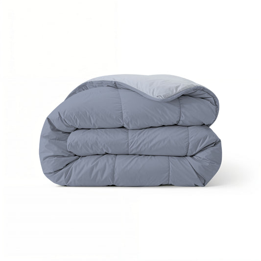Het Zelesta Comfort Duo Dekbed in ijsblauw & zachtblauw, met een doorgestikt dessin geïnspireerd op klassieke dekbedden, is netjes opgevouwen en perfect als laagje voor het hele seizoen, afgebeeld tegen een effen witte achtergrond.