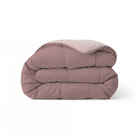 Het Zelesta Comfort Duo Dekbed in oudroze en lichtroze is gevouwen afgebeeld, waarbij het tweekleurige ontwerp goed uitkomt tegen een effen witte achtergrond.