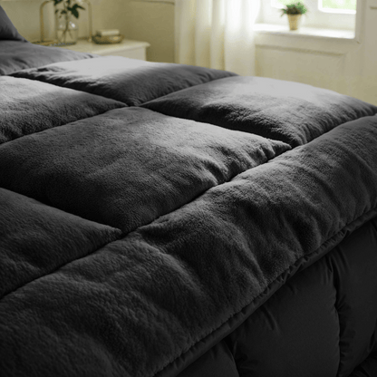 Close-up van het donkergrijze Zelesta Teddybed - Antraciet pluche dekbed op een netjes opgemaakt bed in een zacht verlichte slaapkamer.