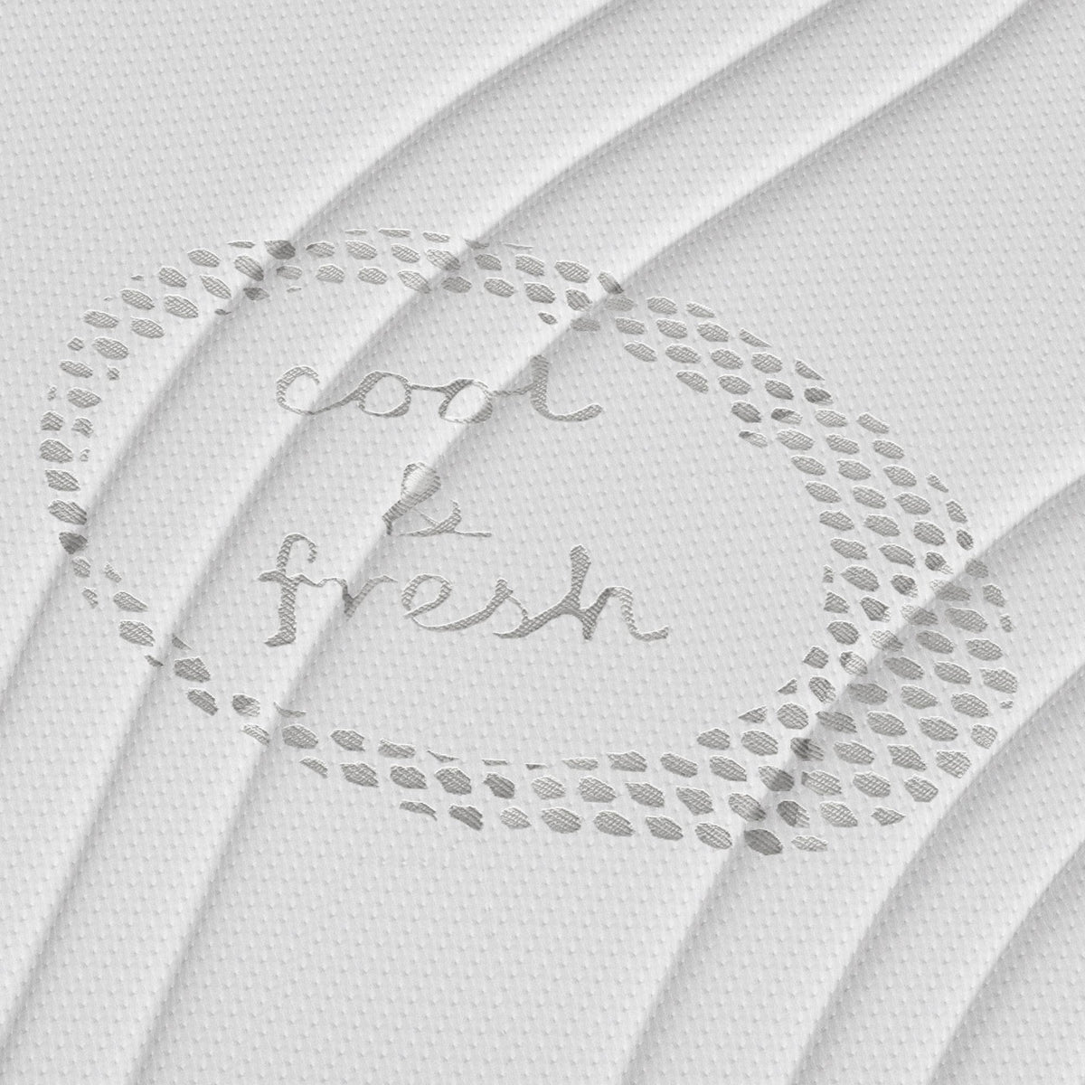 Gestructureerde witte stof met ronde stippen en "cool & fresh" handgeschreven in het midden. Subtiele plooien roepen het comfort op van een koele frisse tijk op de Topdekmatras - NASA Schuim Cool Fresh Tijk.