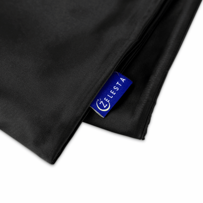 Een opgevouwen Zelesta Sleeping Beauty Set - Universal Black kussensloop met een blauw LEESTA label is gedeeltelijk zichtbaar.