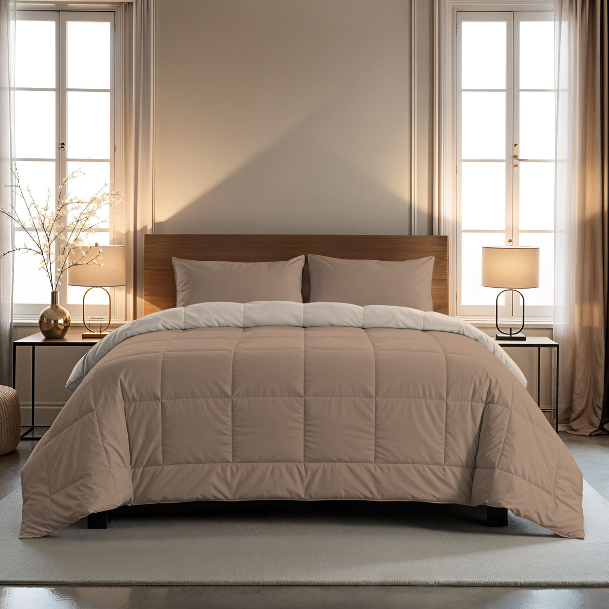 Een netjes opgemaakt bed met het Zelesta Comfort Duo Dekbed - Terra & Zand en twee kussens, geflankeerd door bijzettafeltjes met lampen, in een zacht verlichte slaapkamer met grote ramen en transparante gordijnen.