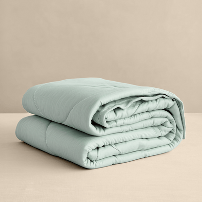 Een Zelesta Cooling Blanket in mintgroen is netjes gestapeld op een beige oppervlak met een effen beige achtergrond.