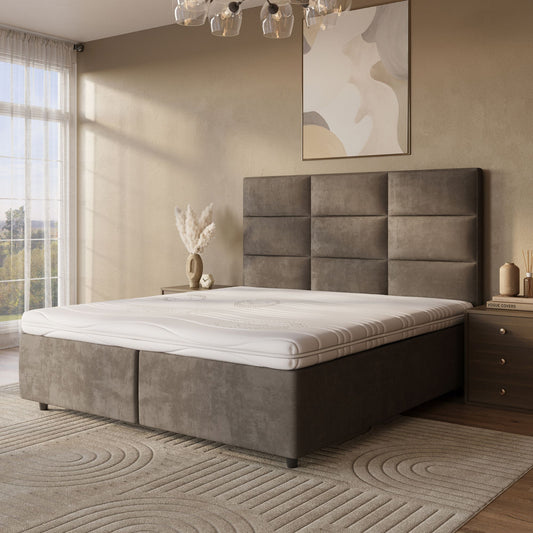 Een moderne slaapkamer met een groot gestoffeerd bed met de Topdekmatras - Comfortschuim Cool Fresh Tijk, neutraal beddengoed, een nachtkastje met boeken, een vaas met gedroogde planten, abstracte muurkunst en transparante gordijnen voor het raam.