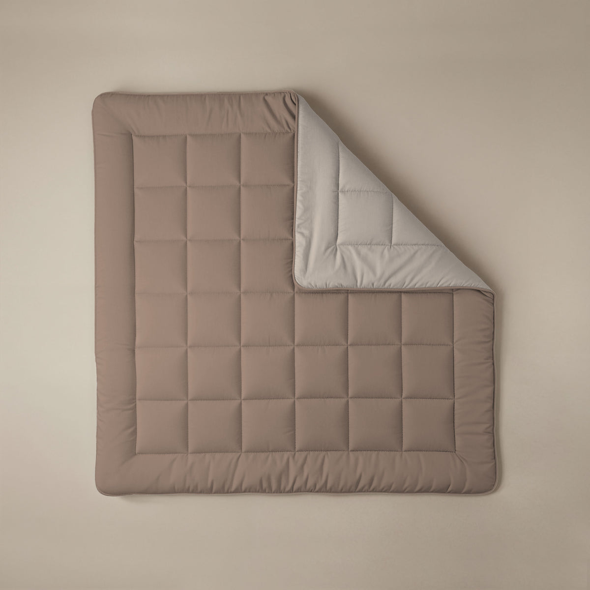 Het Zelesta Comfort Duo Dekbed - Terra & Zand is een bruine gewatteerde deken met een rasterpatroon, geïnspireerd op klassieke dekbedden. De deken is gedeeltelijk opgevouwen zodat de lichtgrijze onderkant zichtbaar wordt, en plat neergelegd voor een look het hele seizoen door.