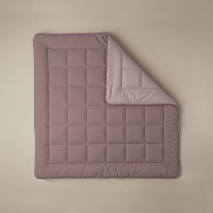 Het Zelesta Comfort Duo Dekbed in oudroze & lichtroze, met afgeronde hoeken en een doorgestikt dessin, wordt getoond op een beige oppervlak met een hoek omgevouwen om de lichtere kant te laten zien.