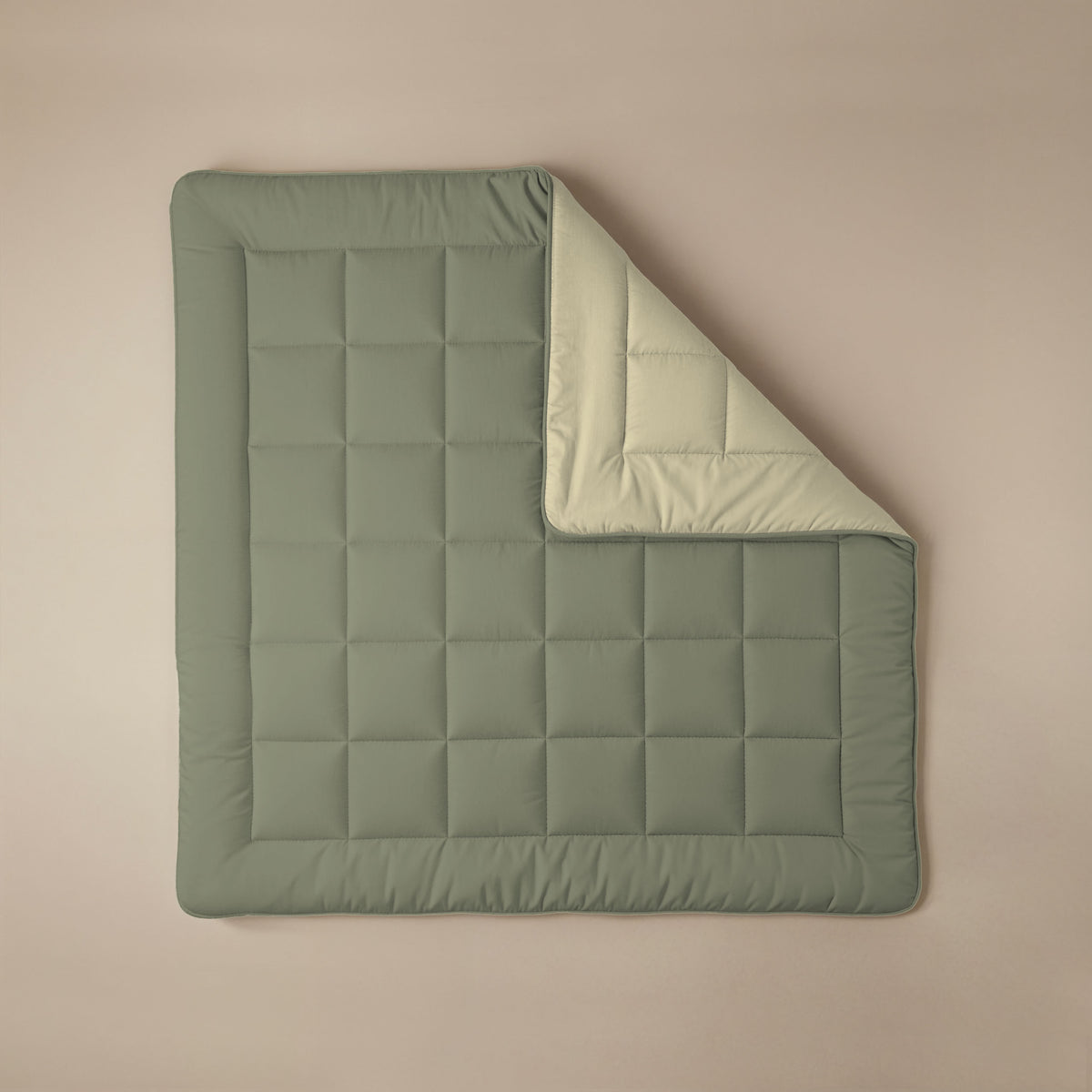 Het Zelesta Comfort Duo Dekbed in olijfgroen met een gridpatroon ligt plat op een beige ondergrond, met één hoek omgeslagen om de crèmekleurige onderkant te tonen - een all season alternatief voor klassieke dekbedden.