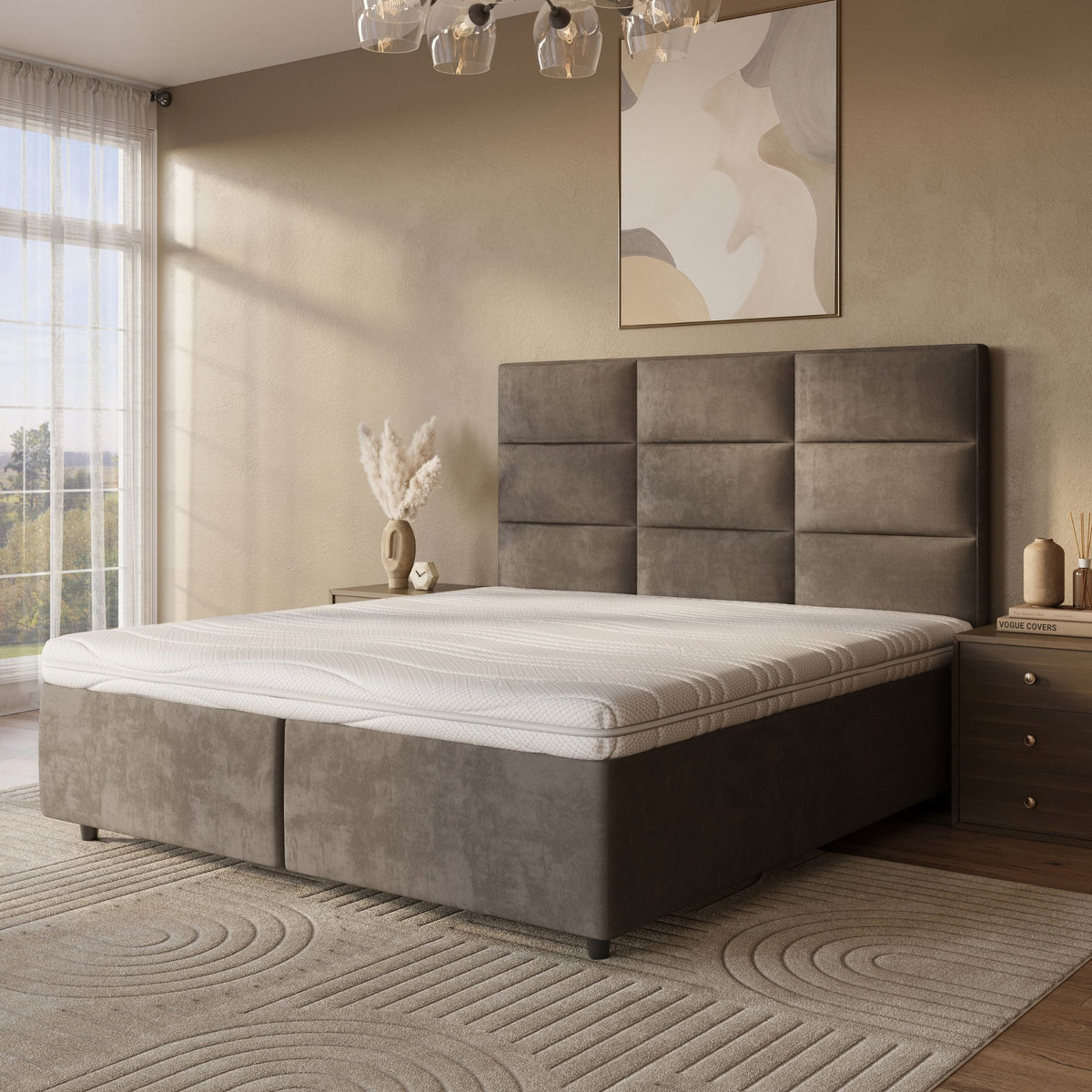 Moderne slaapkamer met een groot gestoffeerd bed met de Topdekmatras - Latex Schuim Bamboe Tijk voor drukverlagende ondersteuning, abstracte muurkunst, twee nachtkastjes, decoratieve vaas, neutraal vloerkleed met patroon en zonlicht dat door transparante gordijnen naar binnen schijnt.