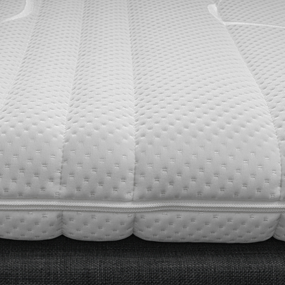 Close-up van de Silver Line Topper - Hybrid Koudschuim, een witte, gestructureerde matras met doorgestikt patroon en zichtbare stiksels, rustend op een bedbodem van donkere stof, gemaakt van natuurlijke materialen voor een gezonde slaapomgeving.
