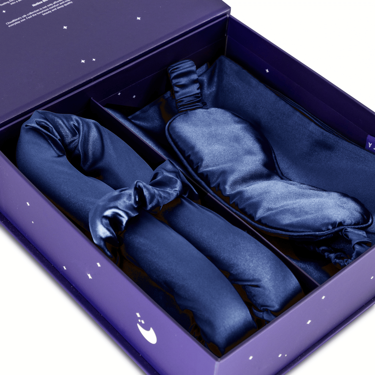 De Zelesta Sleeping Beauty Set - Bliss Blue bevat een marineblauw satijnen oogmasker en twee bijpassende scrunchies in een paars doosje, perfect voor een anti-verouderingsritueel voor het slapengaan.