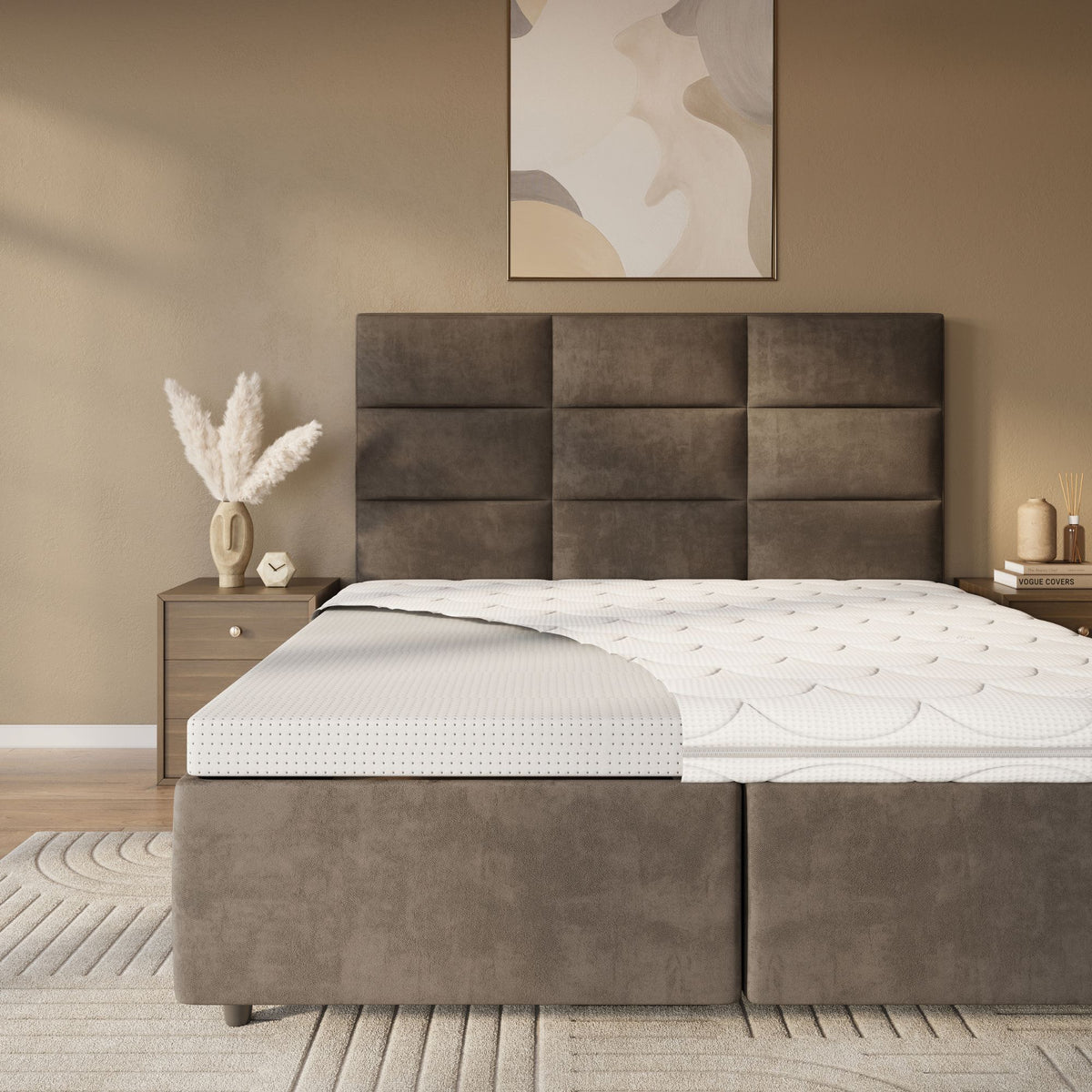 Een moderne slaapkamer met een bruin gestoffeerd bed, een Topdekmatras - Latex Schuim Tencel Tijk met een hoekuitsparing, een nachtkastje met pampagras in een vaas en abstracte muurkunst.