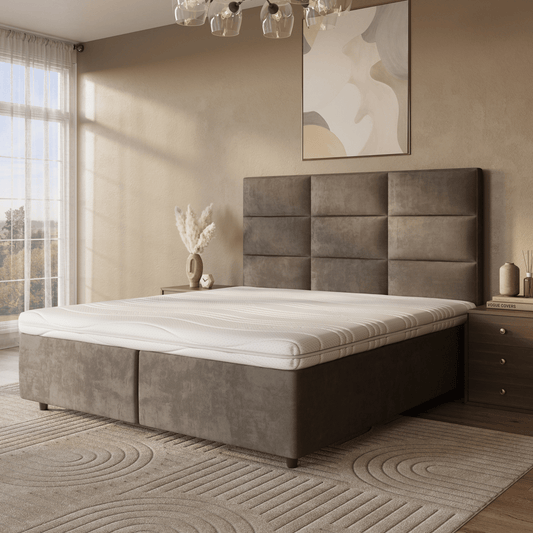 Een moderne slaapkamer met een groot gestoffeerd bed met daarop de Topdekmatras - Hybride Koudschuim Cool Fresh Tijk voor drukverlagend comfort, neutraal beddengoed, een nachtkastje met boeken en vaas, muurkunst en natuurlijk raamlicht.