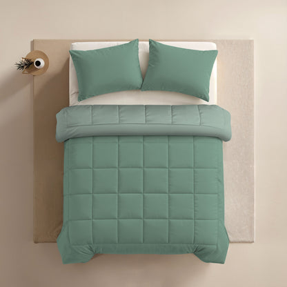 Een netjes opgemaakt bed met Zelesta Comfort Duo Dekbed in mint en lichtgroen, plus bijpassende groene kussens, van bovenaf gezien naast een kleine ronde tafel met een plant.