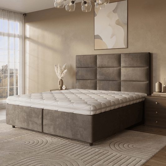 Een moderne slaapkamer met een groot gestoffeerd bed, Topdekmatras - Hybride Koudschuim Tencel Tijk voor drukverlagend comfort, gewatteerde matras, nachtkastje met boeken, neutrale inrichting en een raam met transparante gordijnen.