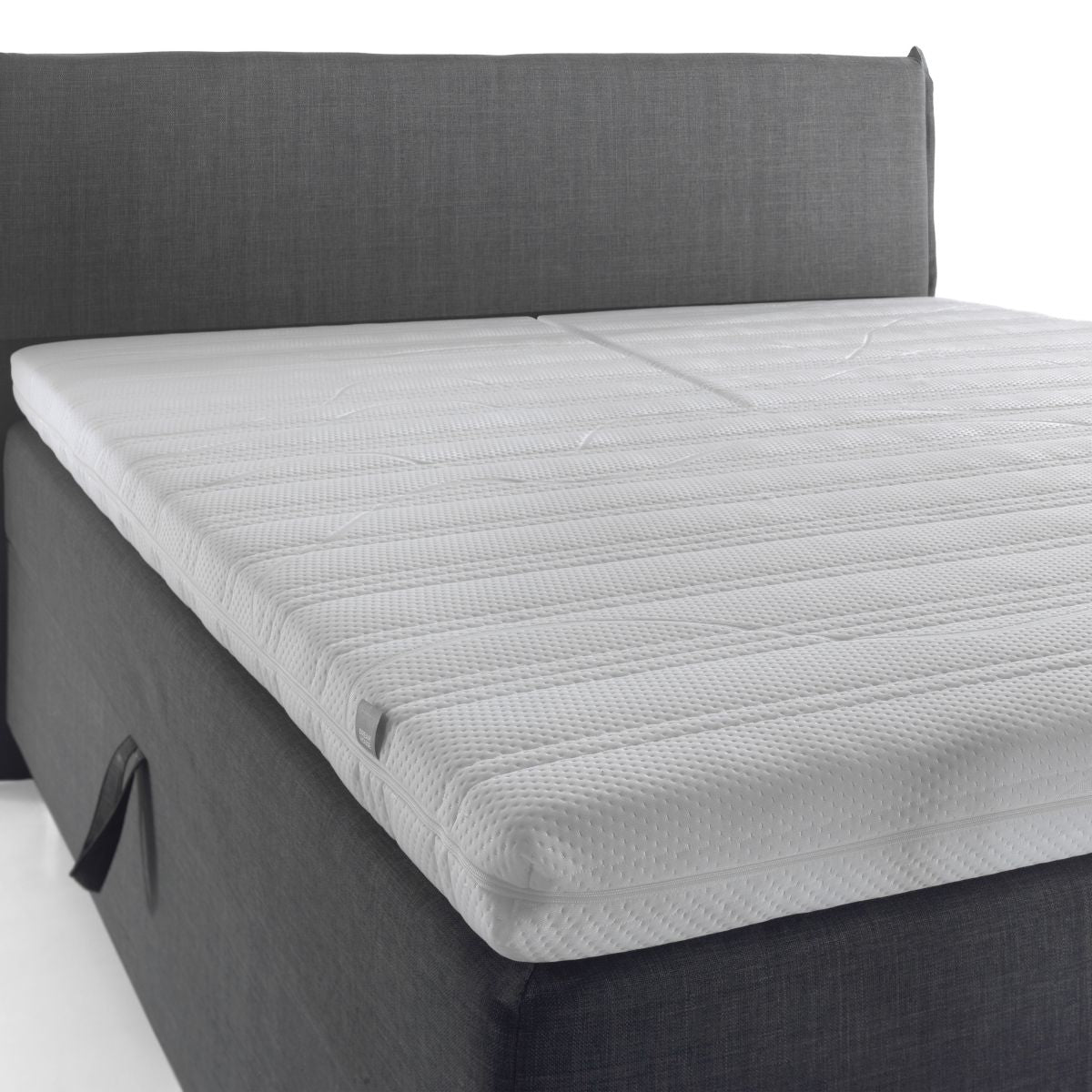 De Silver Line Split Topper - NASA Traagschuim biedt drukverlagende ondersteuning voor comfortabel slapen, met zijn witte matrastopper met structuur die netjes op een grijs gestoffeerd bedframe ligt.