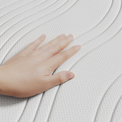 Een hand drukt op de witte, gestructureerde Topdekmatras - NASA Schuim Aloë Vera Tijk, met golvende patronen en NASA-schuim voor drukverlagende ondersteuning.