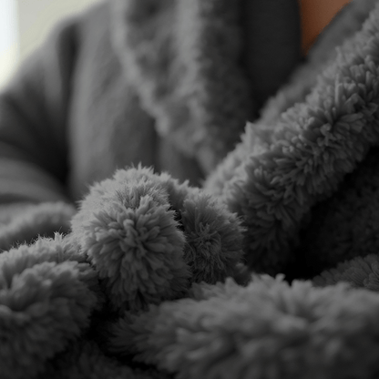 Close-up van een persoon in de Teddy Badjas - Antraciet; de zachte, comfortabele badjas toont duidelijk de dikke tekstuur en vezels.