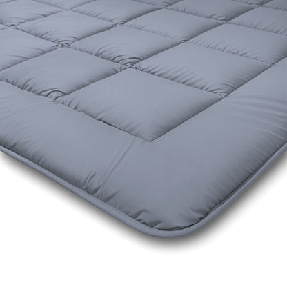 Een close-up van een grijze, gewatteerde matrastopper met vierkante stiksels en een zacht oppervlak, ideaal om onder het Zelesta Comfort Duo Dekbed - Ijsblauw & zachtblauw te leggen of te combineren met beddengoed voor alle seizoenen.