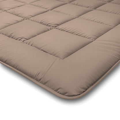 Een close-up van het Zelesta Comfort Duo Dekbed in Terra & Zand, een lichtbruin gewatteerde matrastopper voor alle seizoenen met vierkant gestikte delen en afgeronde hoeken.