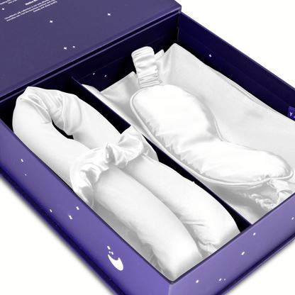 De Zelesta Sleeping Beauty Set - Wonderful White heeft een wit Mulberry zijden slaapmasker voor anti-veroudering en een bijpassende gewatteerde hoofdband, allemaal in een paarse doos met witte ster- en maanontwerpen.
