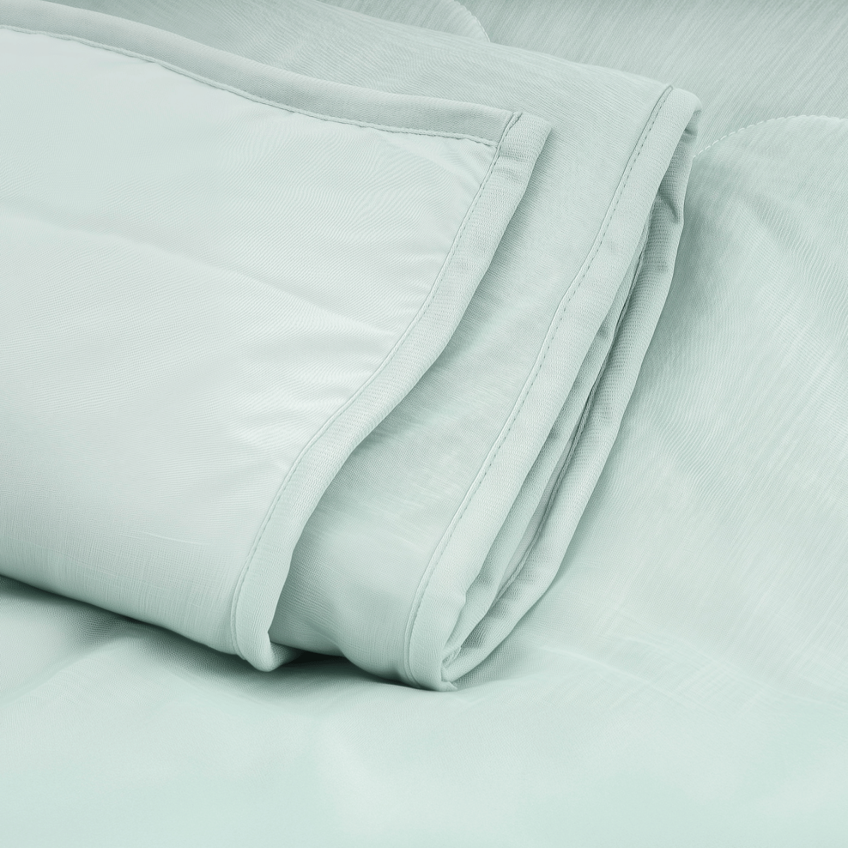 Een netjes opgevouwen mintgroene Zelesta Cooling Blanket rust op een oppervlak van bijpassende stof en biedt een hypoallergene optie voor rustgevend, verfrissend comfort.