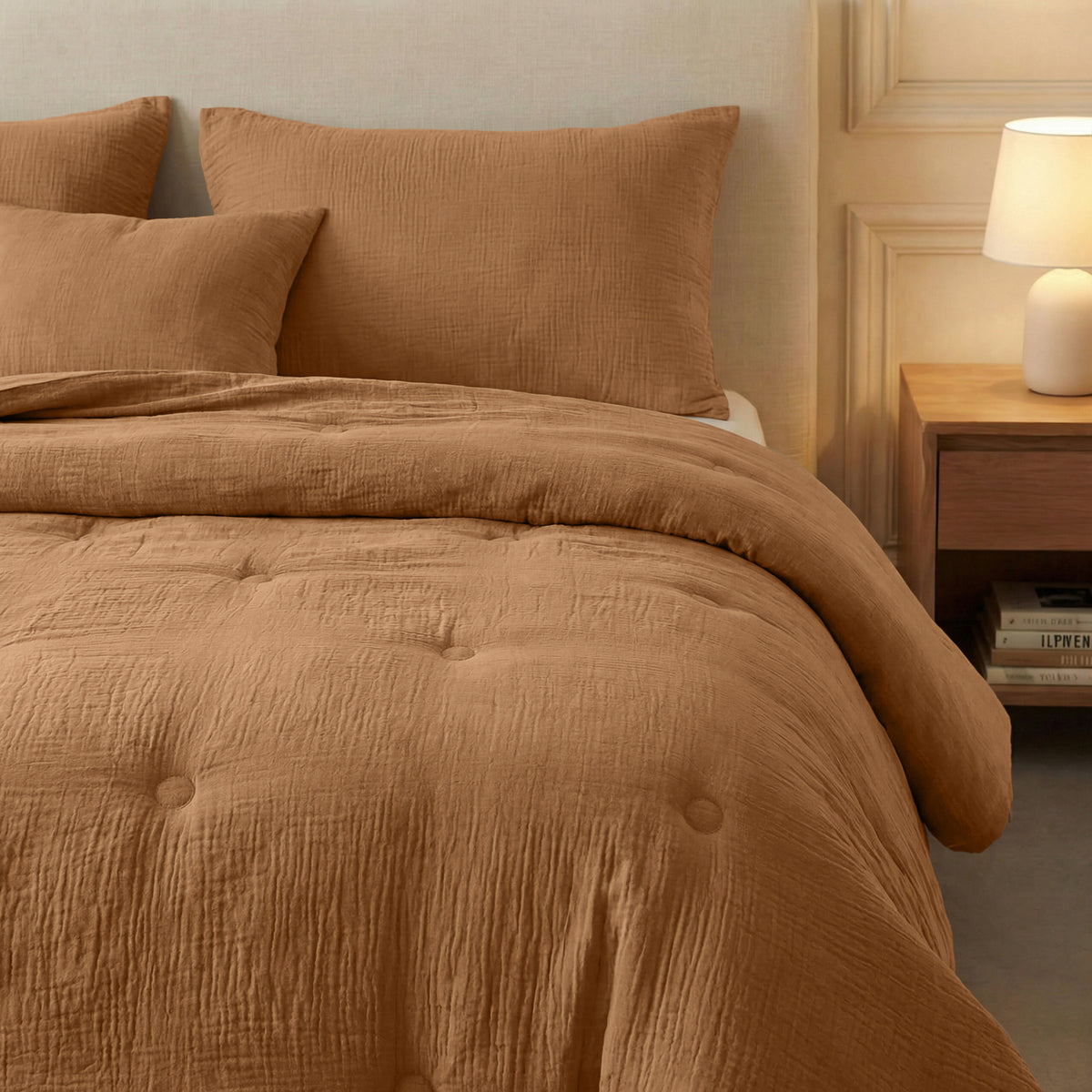 Een keurig opgemaakt bed met de Zelesta Japandibed Katoen Mousseline - Terra, twee kussens, een nachtkastje met een lamp en daaronder boeken opgestapeld.