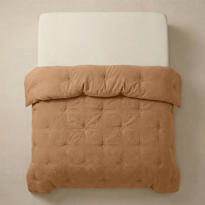 Een keurig opgemaakt bed met een lichtbeige hoofdeinde is voorzien van het Zelesta Japandibed Katoen Mousseline - Terra, een bruin getuft Japandi dekbed, van boven afgebeeld tegen een effen achtergrond.