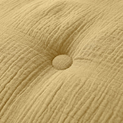 Close-up van het Zelesta Japandibed Katoen Mousseline kussen in oker, met een centrale knoop en subtiele stofplooien.