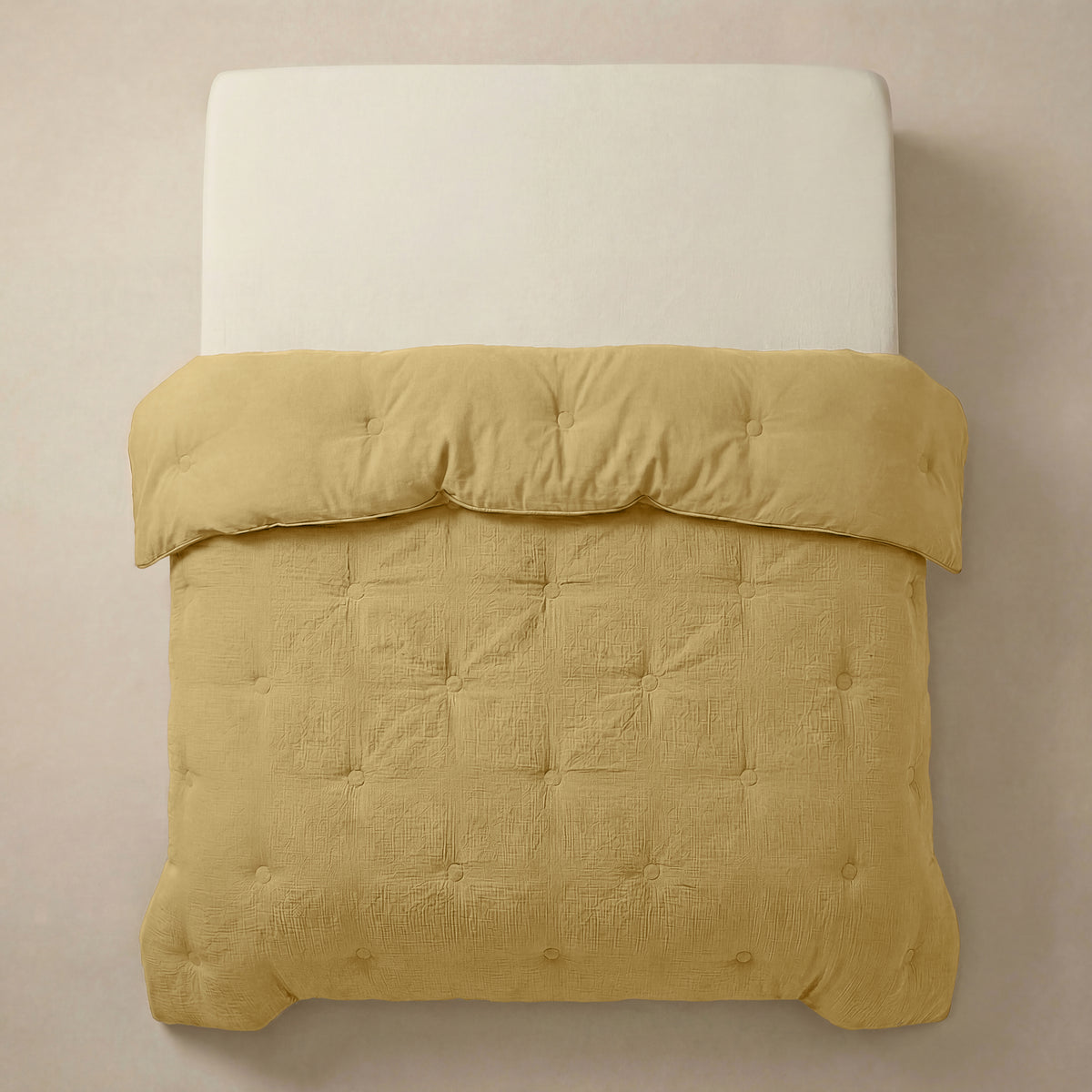 Het Zelesta Japandibed Katoen Mousseline - Oker heeft een witte matras en een getuft, goudgeel Japandi dekbed van zachte katoenmousseline, van bovenaf gezien tegen een neutrale achtergrond.