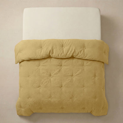 Het Zelesta Japandibed Katoen Mousseline - Oker heeft een witte matras en een getuft, goudgeel Japandi dekbed van zachte katoenmousseline, van bovenaf gezien tegen een neutrale achtergrond.