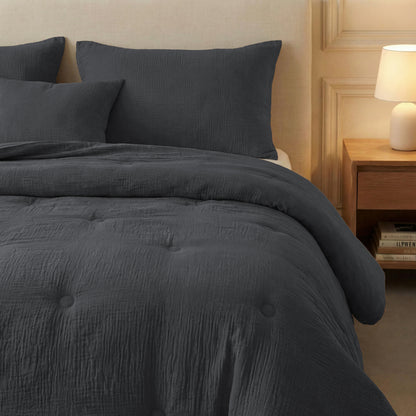 Een keurig opgemaakt bed met de Zelesta Japandibed Katoen Mousseline in antraciet, bijpassende kussens, een beige hoofdeinde en een houten nachtkastje met daarop een lamp en gestapelde boeken.