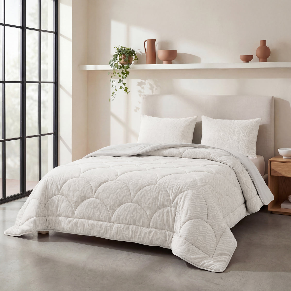Een minimalistische slaapkamer is voorzien van een netjes opgemaakt bed met het Zelesta Flanel Luxe - Creme dekbed, twee kussens, een nachtkastje, decoratief aardewerk, een potplant en grote ramen die de ruimte vullen met natuurlijk licht.