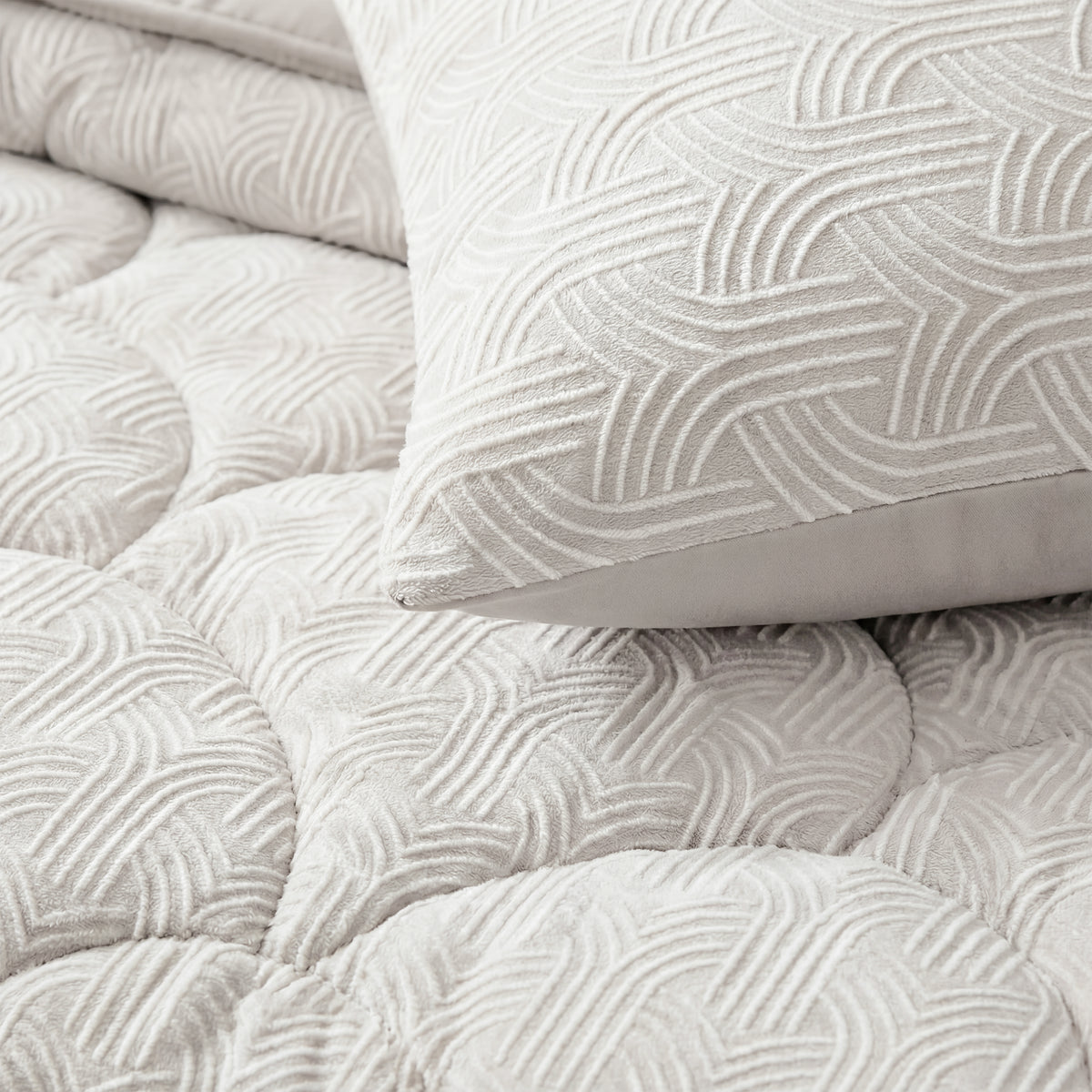 Close-up van Zelesta Flanel Luxe - Crèmekussen en doorgestikt beddengoed met een verhoogd geometrisch patroon in lichtbeige, dat het ultrazachte comfort biedt van een microvezel dekbed.