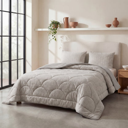 Een netjes opgemaakt bed met het Zelesta Flanel Luxe - Taupe & Grijs dekbed en twee kussens staat tegen een beige muur met een plank met decoratieve vazen en een potplant. Natuurlijk licht stroomt naar binnen door de grote ramen.