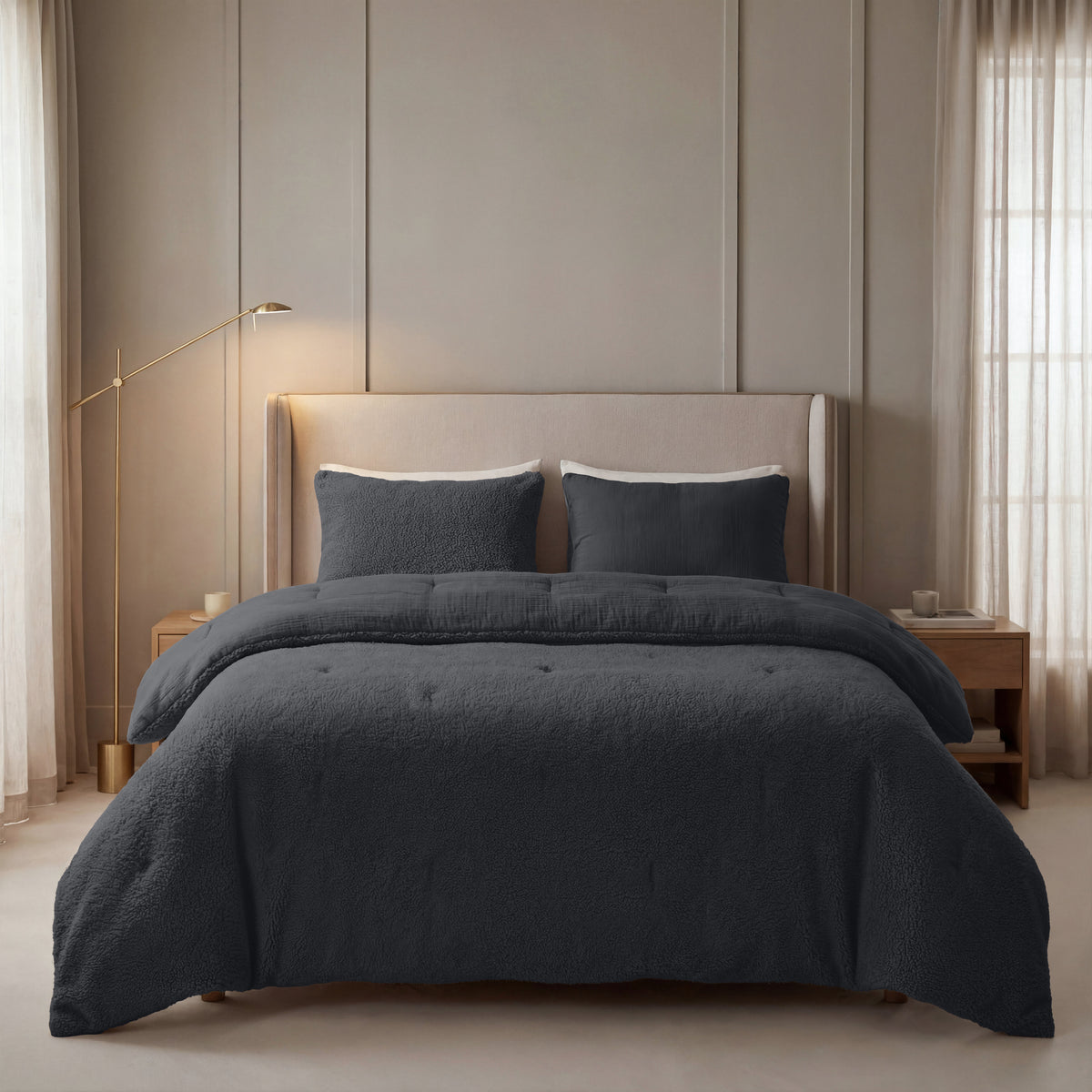 Een netjes opgemaakt bed met Zelesta Teddy Katoen Mousseline beddengoed in antraciet, twee bijpassende kussens, een beige gestoffeerd hoofdeinde en houten nachtkastjes in een zacht verlichte, neutrale slaapkamer.
