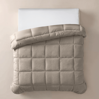 Een netjes opgemaakt bed met een wit kussen en het Zelesta Teddybed - Taupe, met een beige rasterpatroon, omgeslagen aan de bovenkant, gefotografeerd van bovenaf.