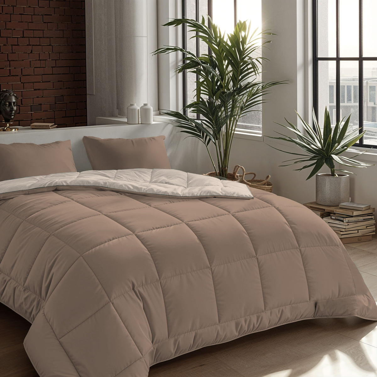 Op een netjes opgemaakt bed staat het Zelesta Comfort Duo Dekbed - Terra & Zand in een moderne slaapkamer met grote ramen, kamerplanten en een bakstenen accentmuur - een ideale keuze voor comfort het hele seizoen door of om klassieke dekbedden te laten zien.