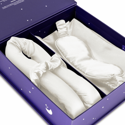 De Zelesta Sleeping Beauty Set - Pearl White wordt geleverd in een paarse geschenkverpakking met een witte satijnen slaapmasker en bijpassende scrunchie, elk netjes gerangschikt in zijn eigen compartiment.