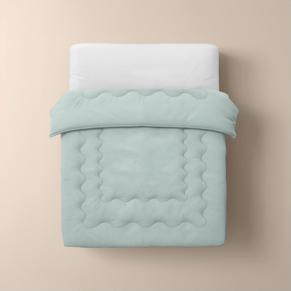 Een netjes opgemaakt bed met een wit kussen, wit laken en de mintgroene Zelesta Cooling Blanket op een beige achtergrond, van bovenaf gezien.