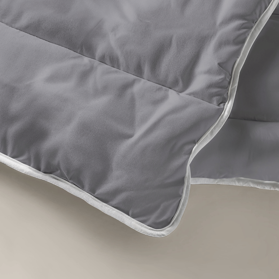 Een close-up van het Zelesta Royalbed - Antraciet laat de zachte textuur, witte bies en gelaagde constructie zien - een echt all-season dekbed en overtrek in één voor comfort het hele jaar door.