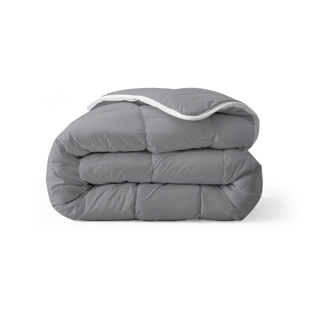 Een netjes opgevouwen antraciet dekbed, het Zelesta Royalbed all-season dekbed en overtrek in één, rust elegant tegen een effen witte achtergrond.