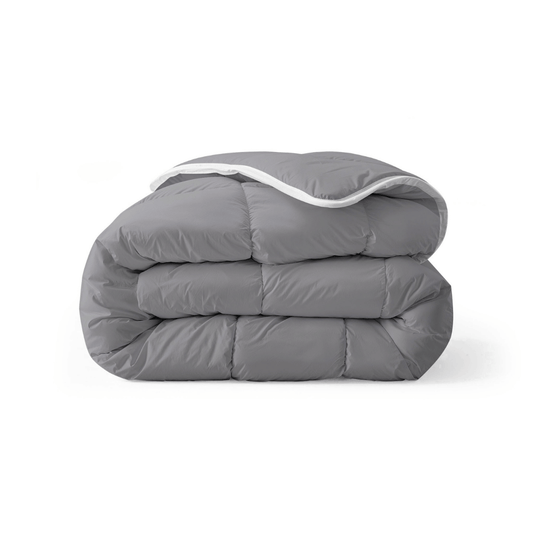 Een netjes opgevouwen antraciet dekbed, het Zelesta Royalbed all-season dekbed en overtrek in één, rust elegant tegen een effen witte achtergrond.
