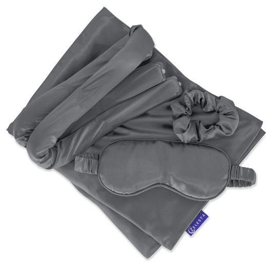 De Zelesta Sleeping Beauty Set - Amazing Anthracite, een gevouwen set van grijze moerbeizijde met een anti-verouderings kussensloop, slaapmasker, haar scrunchie en omslagdoek voor lang haar, wordt netjes gepresenteerd op een witte achtergrond.