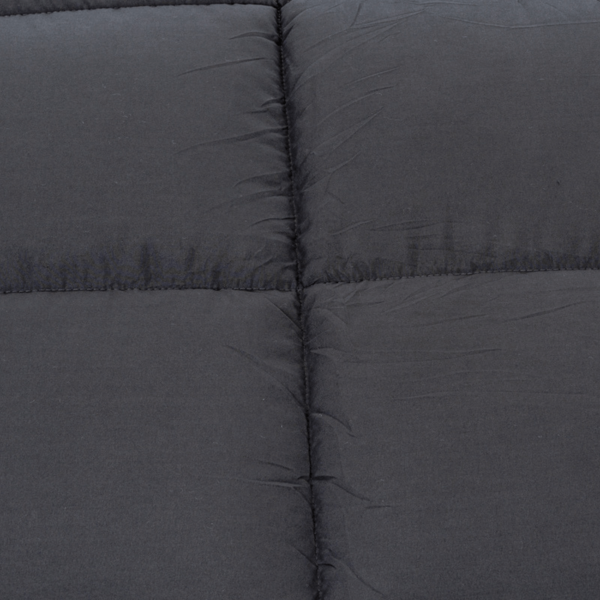 Close-up van donkergrijze gewatteerde stof met zichtbare vierkante stiksels, ideaal voor een knus dekbed zoals het Zelesta Teddybed - Antraciet.