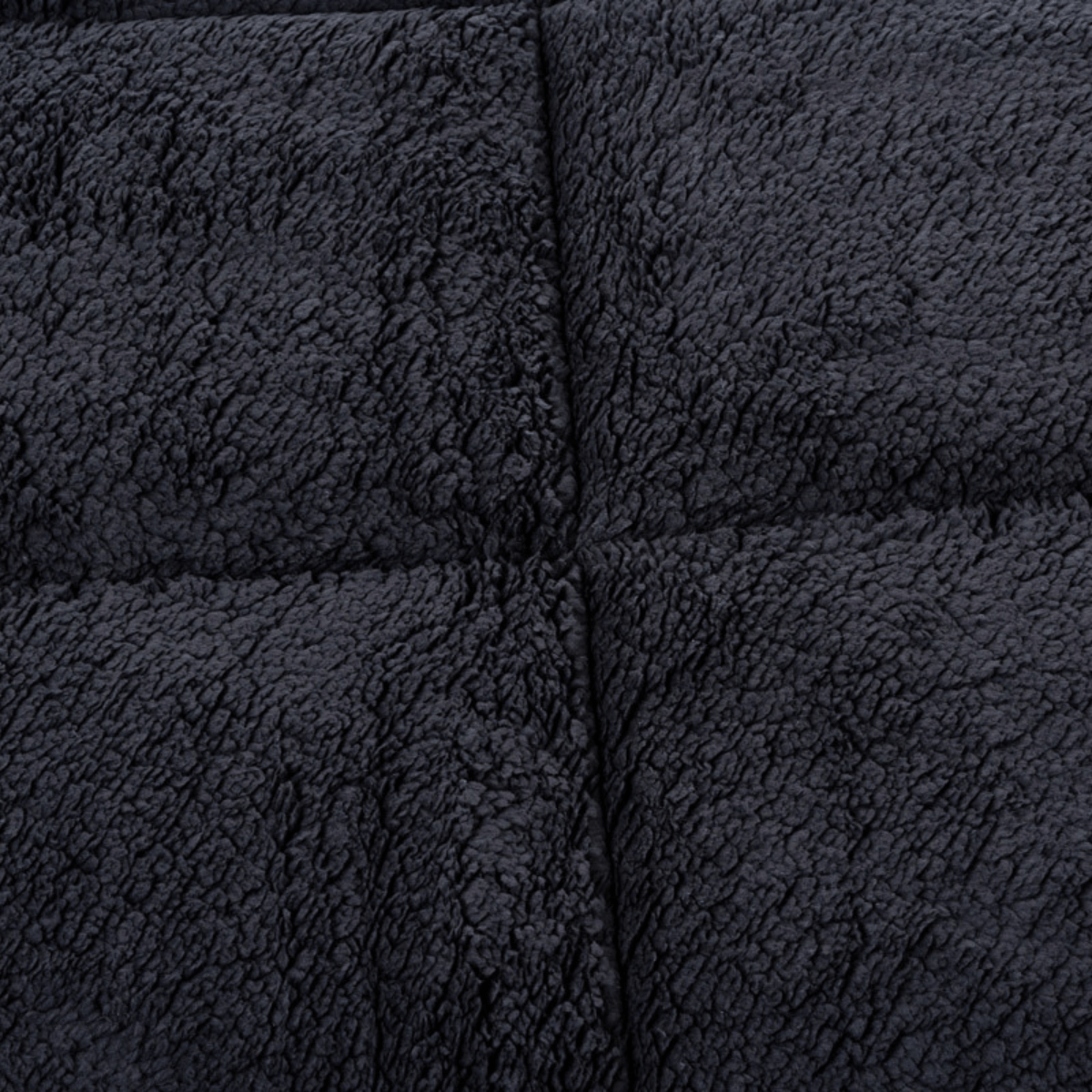 Close-up van het Zelesta Teddybed - Antraciet, met donkergrijze teddystof met structuur en gestikte kruisnaden, ideaal voor knus comfort.